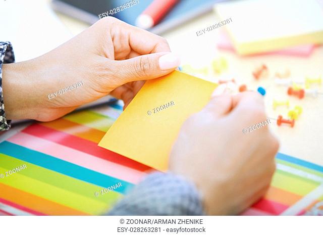 Woman at office holding adhesive note