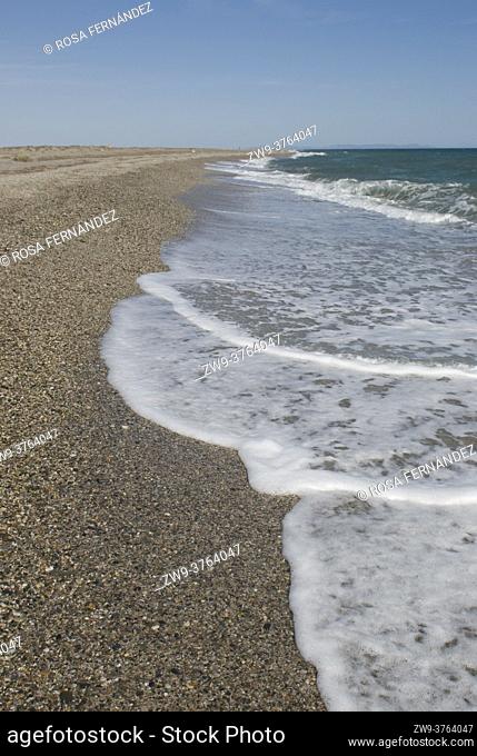 Punta Entinas Sabinar Beach, with a pebble soil and small waves with foam, Roquetas de Mar, Murcia Region, Spain