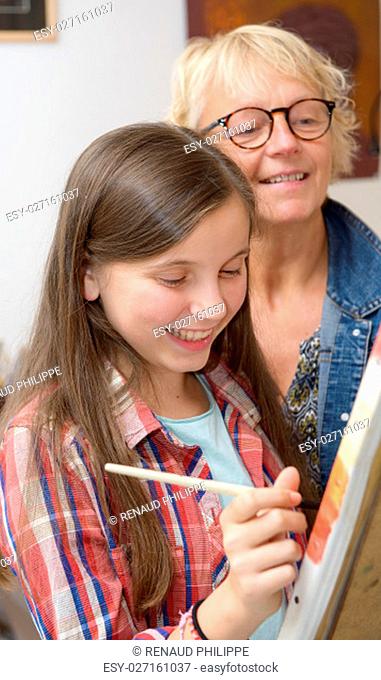Smiling young teen girl painting with her teacher