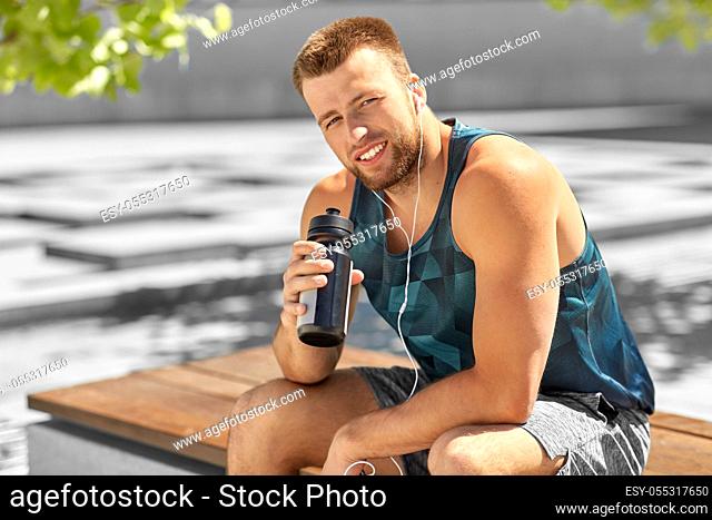 sportsman with earphones and bottle in city