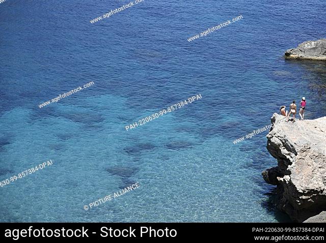 29 June 2022, Spain, Deia: Tourists sunbathing and swimming at the rocky beach Cala Deia in Mallorca. Photo: Clara Margais/dpa. - Deia/Mallorca/Spain