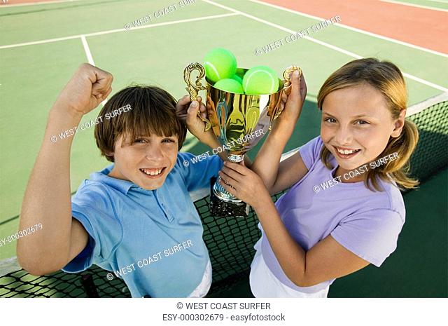 Brother and Sister on tennis court holding up Trophy portrait high angle view
