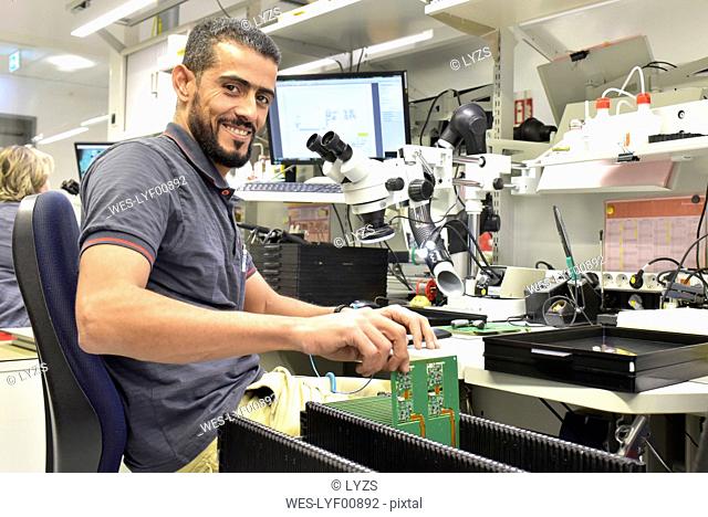 Portrait of smiling man working on quality control in the manufacturing of circuit boards for the electronics industry