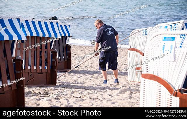 21 May 2020, Schleswig-Holstein, Niendorf/Ostsee: Stephan Muuss, beach chair rental company, aligns beach chairs on the beach at the Baltic Sea with the help of...