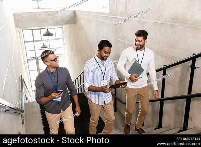 men with conference badges walking upstairs