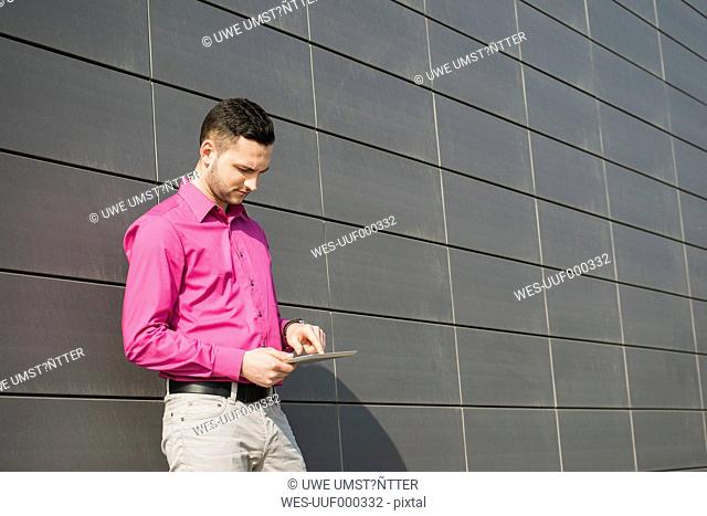 Portrait of man with tablet computer wearing pink shirt