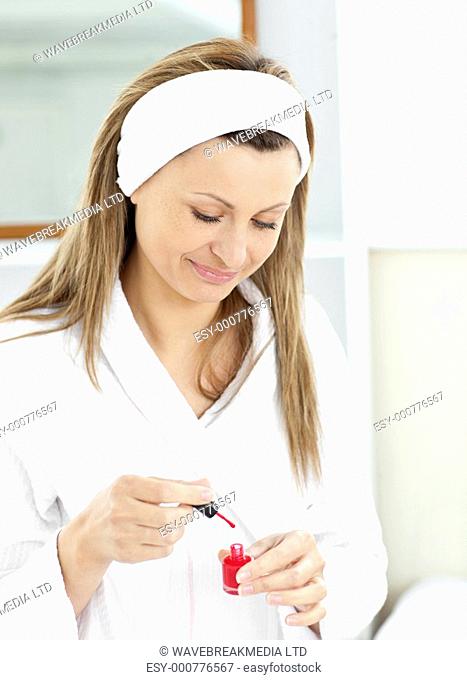 Bright caucasian woman varnishing her fingernails in the bathroom at home