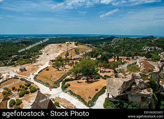 Panoramic view of the castle of Baux-de-Provence at the top of the hill, with the fields and hills of Provence just below