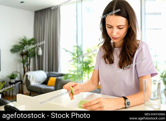 Freelancer sticking adhesive notes on paper at home