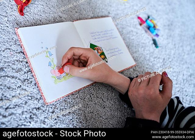 PRODUCTION - 17 April 2023, Berlin: A child draws a heart and flowers in a friend's poetry album. Photo: Annette Riedl/dpa. - Berlin/Berlin/Germany