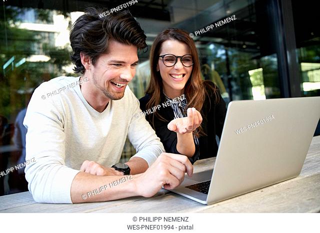 Businessman and happy businesswoman with laptop meeting in the city