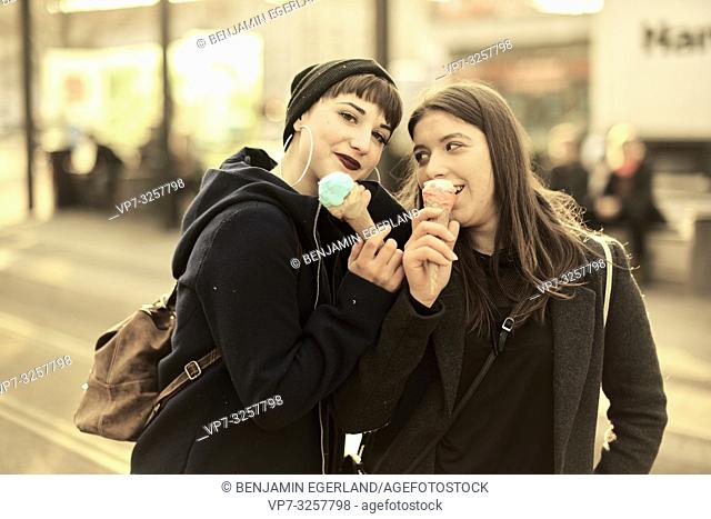two happy friends with ice cream cones during warm winter day, in city Cottbus, Brandenburg, Germany