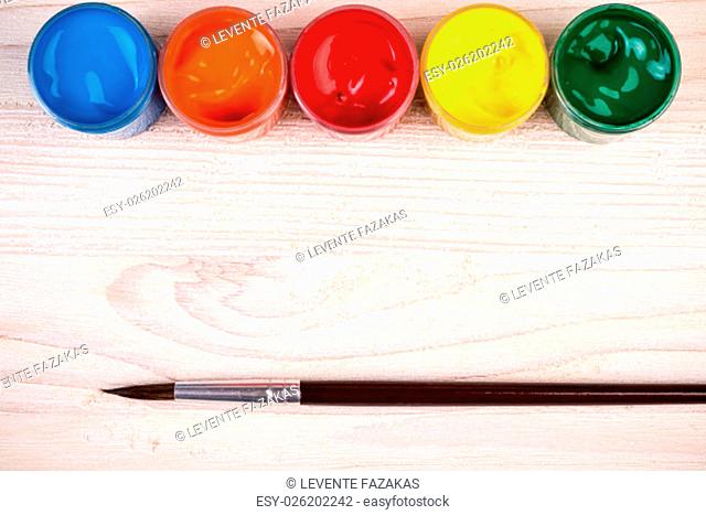 Various color paints with brush on light wooden backgroud