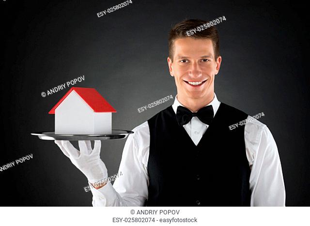 Portrait Of Young Butler Holding Tray With House Model