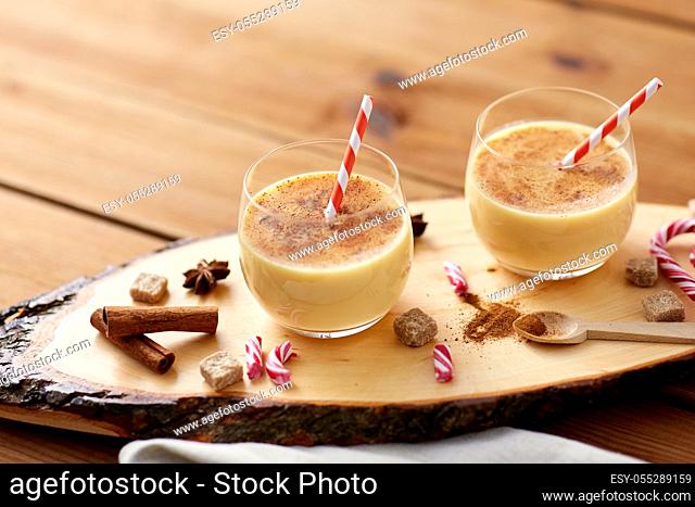 glasses of eggnog, ingredients and spices on wood