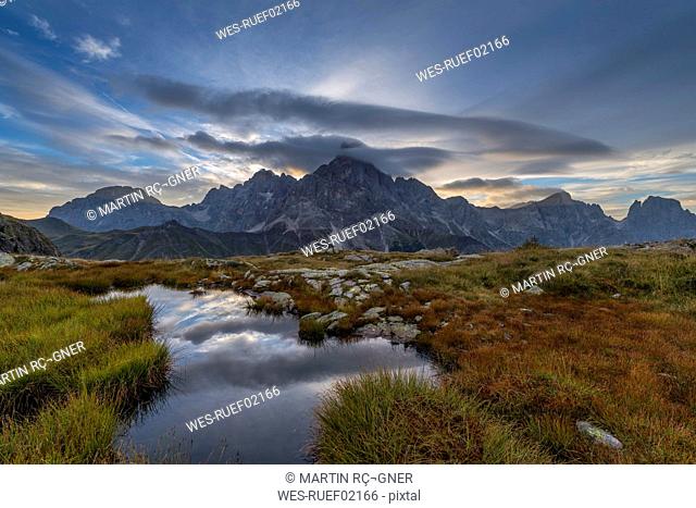 Italy, Dolomites, Passo Rolle, Trentino, Pale di San Martino Mountain group with mountain peak Cimon della Pala with small pond at sunrise