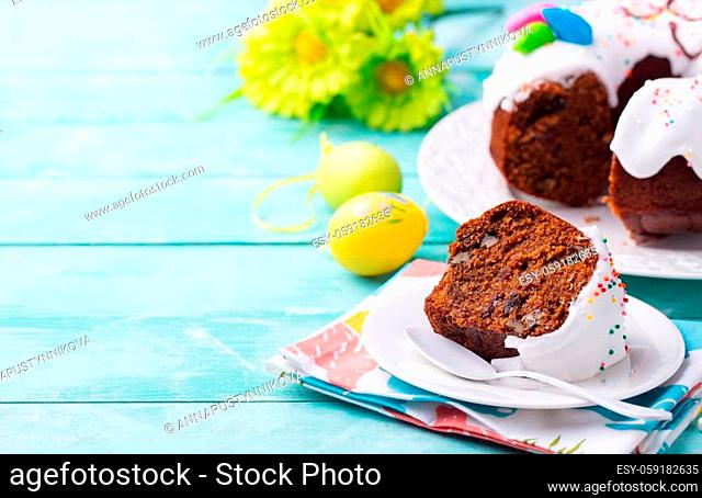Easter cake on a white plate with colorful eggs. Blue wooden background. Copy space