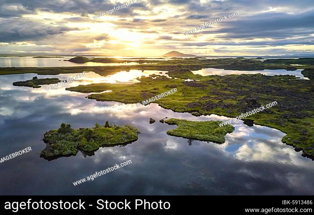 Aerial view of small green islands in the lake, sun breaks through dramatic clouds reflected in the lake, Myvattn, Skútustaðir, Norðurland eystra, Iceland