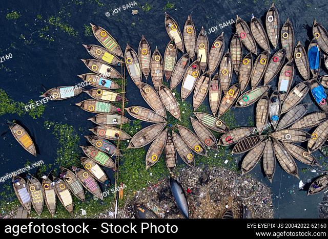 DHAKA, BANGLADESH - APR 20, 2022: Aerial view of Hundreds of wooden boats grouped fan out which look like the petals of a flower for a busy morning commute on...