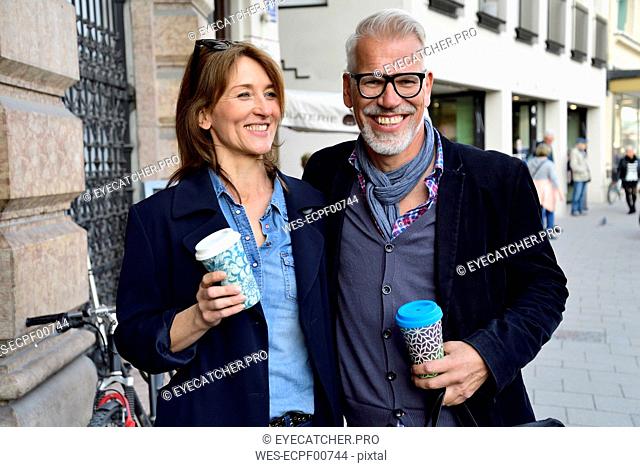 Portrait of smiling mature couple with reusable bamboo cups in the city