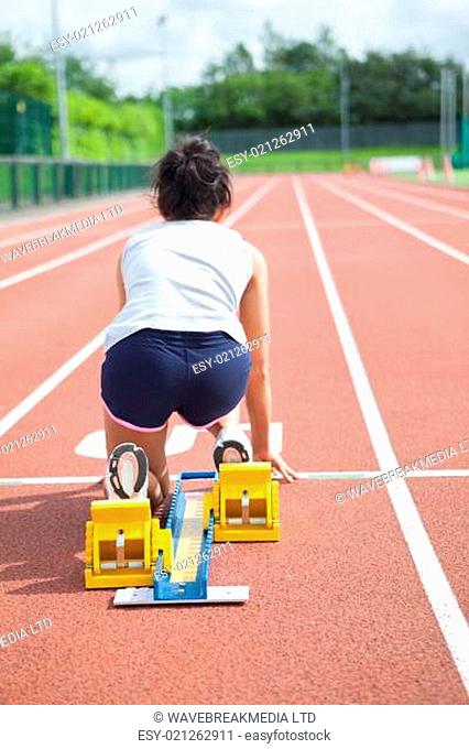 Woman at starting blocks on track field