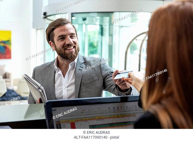 Female receptionist giving credit card to businessman