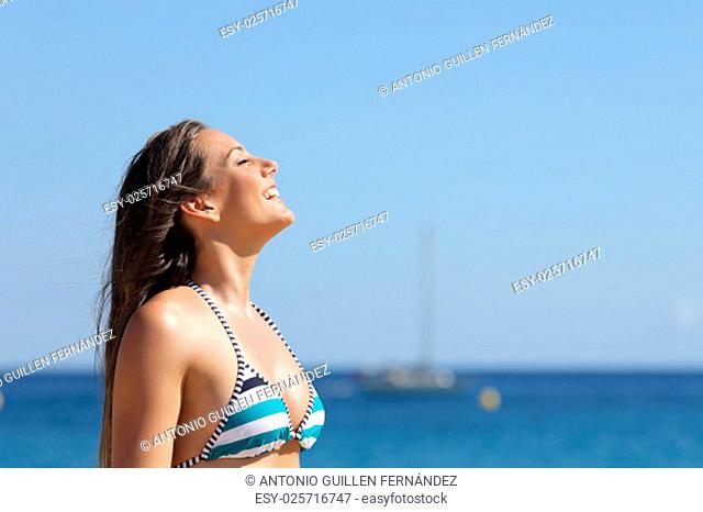 Profile of a woman breathing deep fresh air in summer vacations on the beach