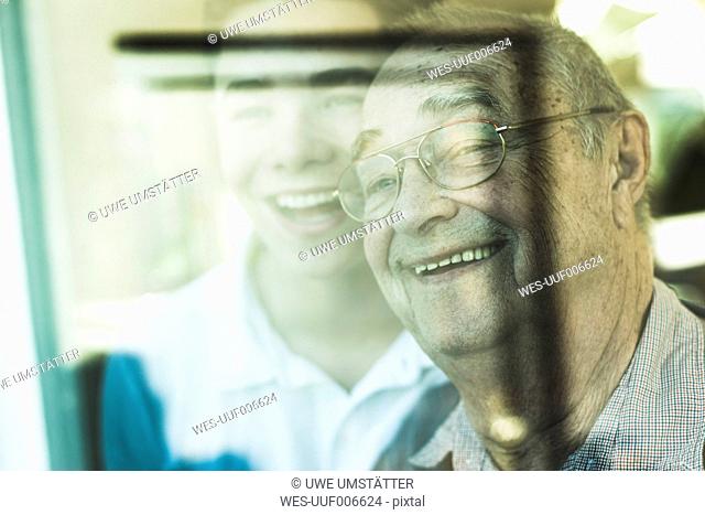 Portrait of senior man and his grandson in the background looking through window