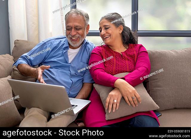 A HAPPY COUPLE SPENDING TIME TOGETHER WHILE USING LAPTOP