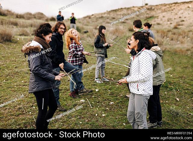 Male and female friends playing with sticks in field