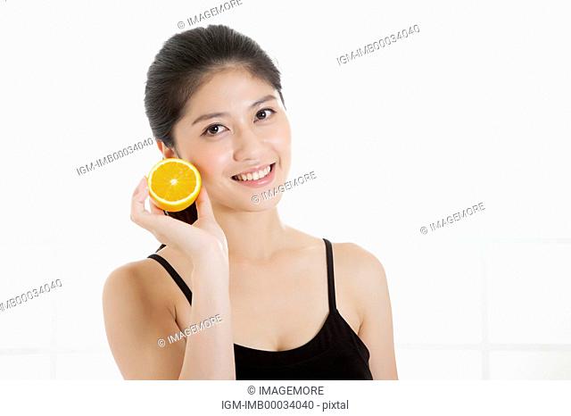 Young woman holding an orange and smiling at the camera