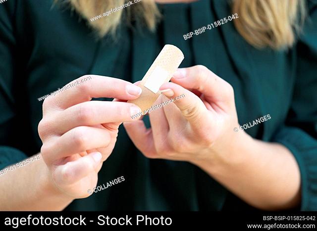 Young woman putting a bandage on her finger