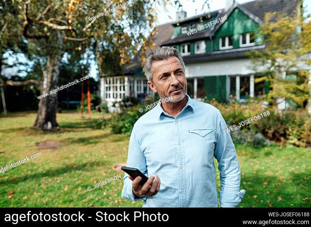 Man holding smart phone at backyard