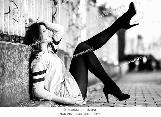 Portrait of funny female model of fashion with high heels sitting on the floor moving her legs