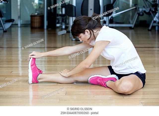 Woman doing stretches on the floor in health club