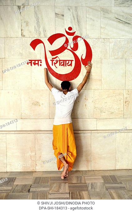 man bowing to OM on temple wall at Jodhpur rajasthan India