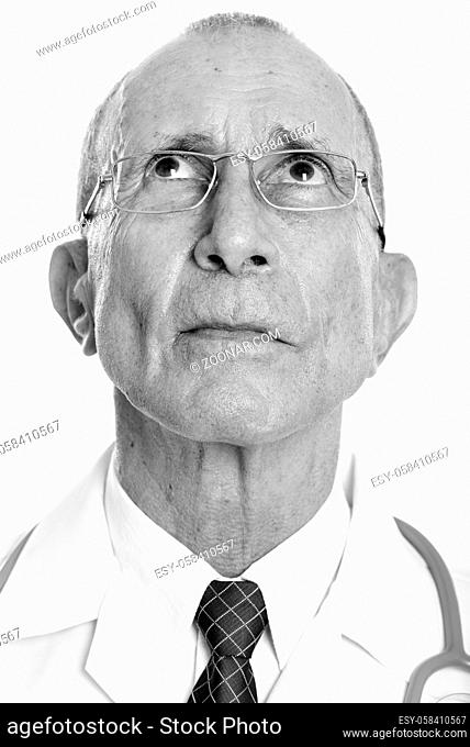Studio shot of senior man doctor isolated against white background in black and white