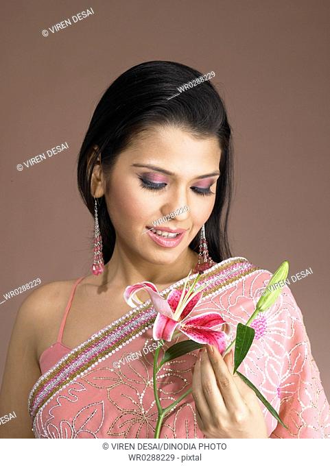 South Asian Indian woman smiling and holding orchid lillium flower MR 702