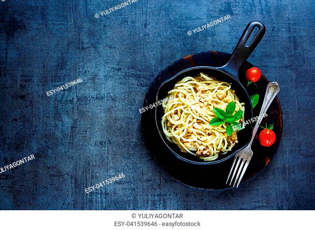 Pasta with creamy crab sauce in black cast iron pan on vintage stone background. Top view. Copy space