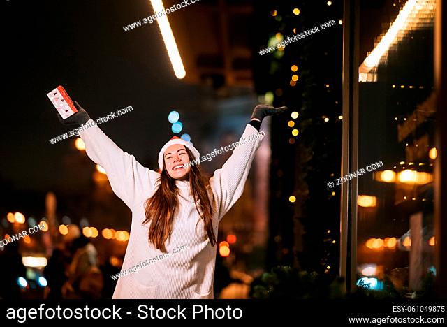 Night street portrait of young beautiful woman acting thrilled. Festive garland lights