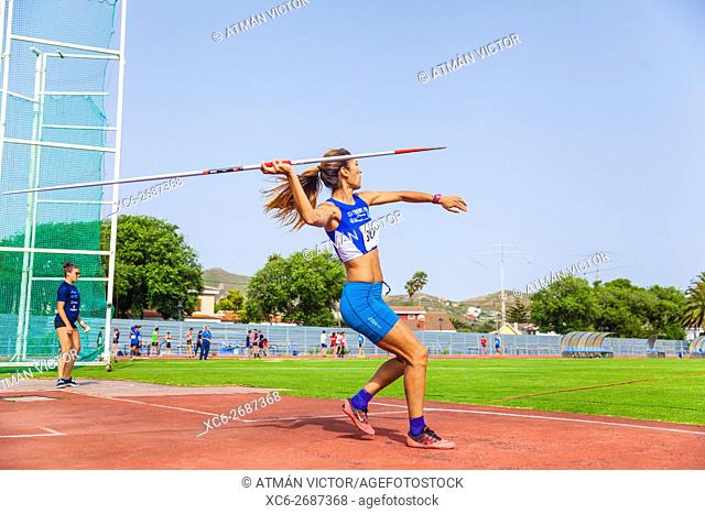 young sportswoman throwing javelin on an athletic piste