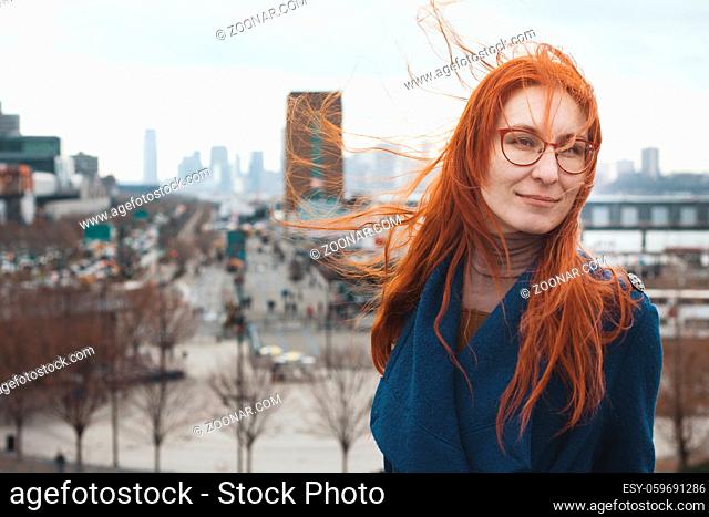 Young woman with red hair in front of New York skyline, telephoto