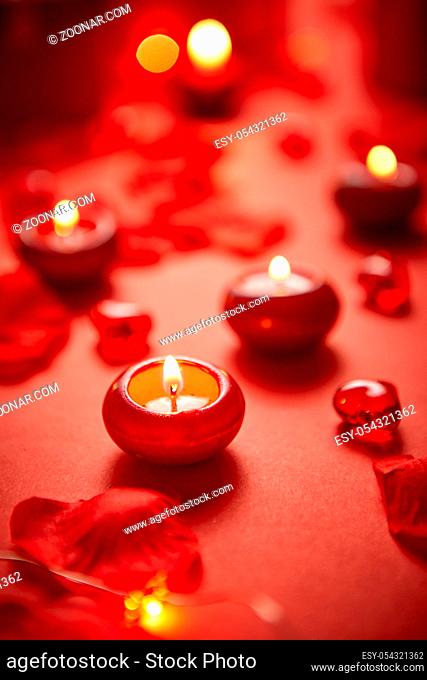 Romantic dinner decoration. Red candles, flower petals, on the table. Selective focus shot. Valentine or Love concept
