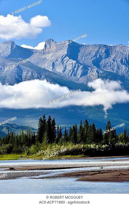 A vertical landscape image of the Canadian rocky mountains of Alberta, Canada with low hanging cloud along the Athabasca river in Jasper National Park