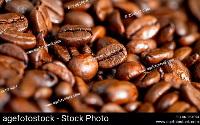 Full frame shot of roasted coffee beans in detail. Group of black aromatic seeds in close up with copy space. Background from a heap of dark fresh grain