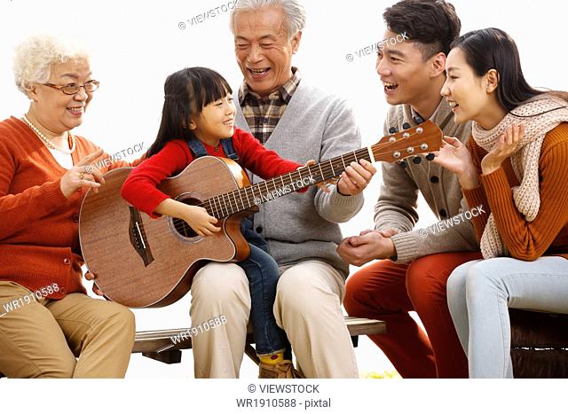 Happy family outdoor play the guitar