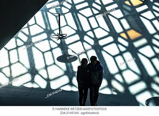 Silhouette of a couple walking through the Harpa Concert Hall and Conference Centre in Reykjavic, Iceland