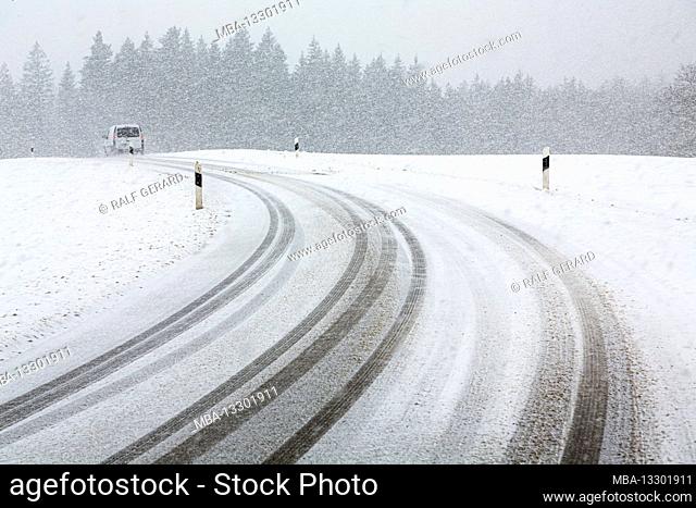 Germany, Bavaria, car on snow-covered country road with tire tracks