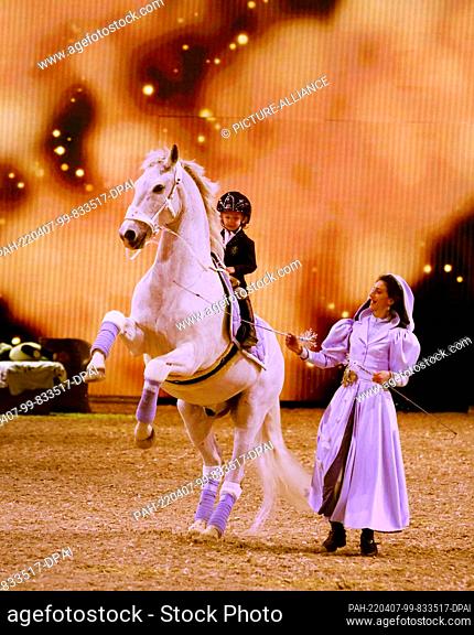 07 April 2022, North Rhine-Westphalia, Essen: In front of a starry sky, a young rider and her riding instructor show their tricks during the Hop Top Show...