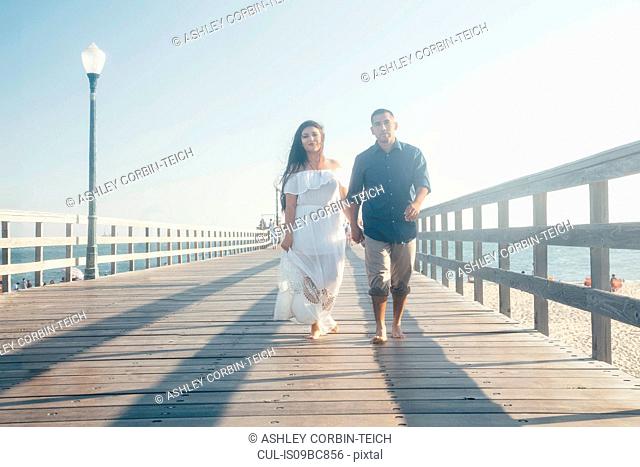 Couple walking along pier, holding hands, Seal Beach, California, USA